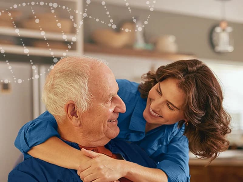 Idoso e familiar em momento afetivo na cozinha